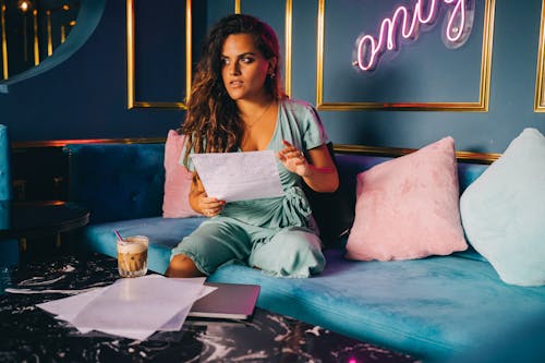 Woman in Teal Dress Sitting on Bed