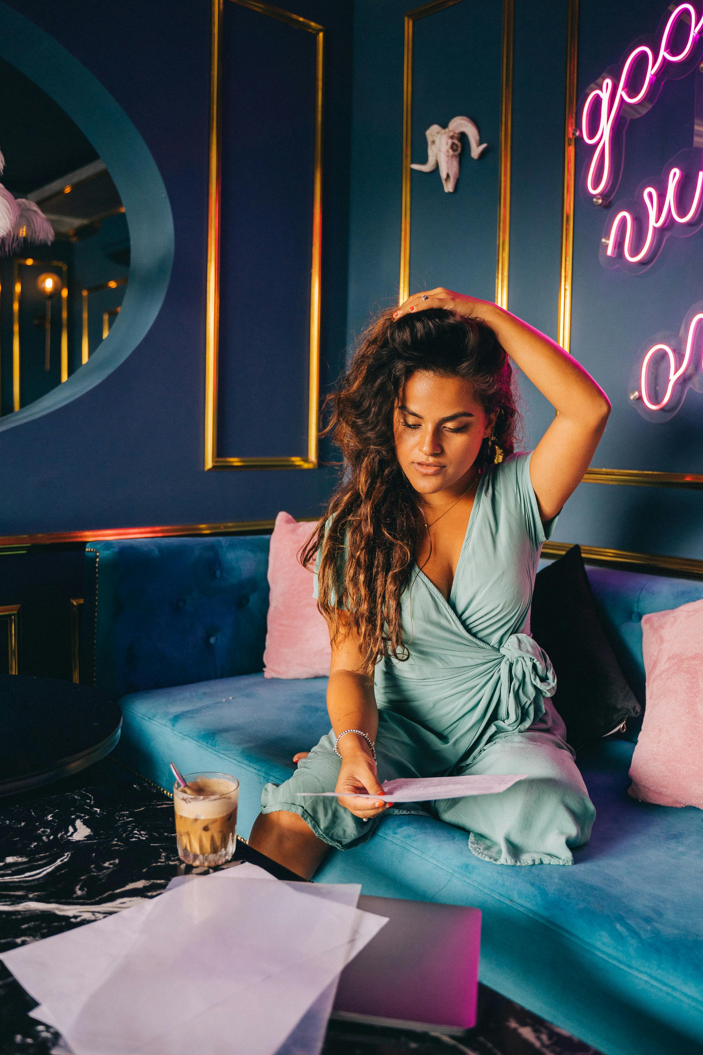 Woman in Gray Dress Sitting on Blue Bed
