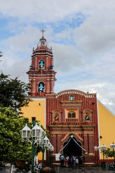 Colorful facade of a traditional Mexican church with visitors entering.