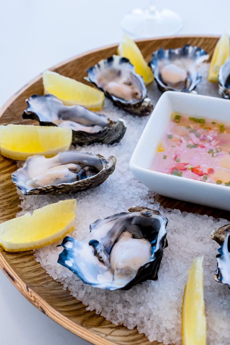 Opened Raw Oysters And Sliced Lemon On A Wooden Plate