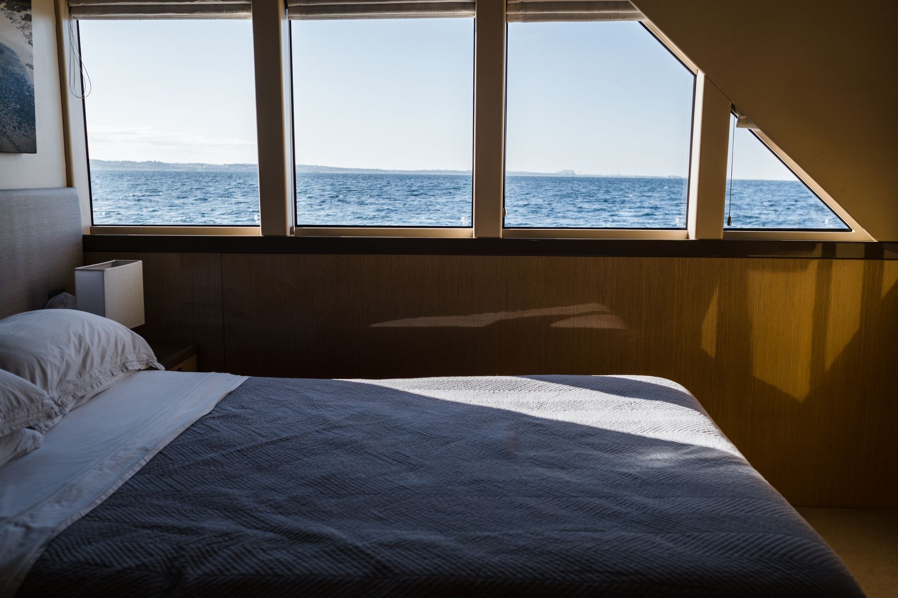 Bedroom with a wide sea view framed by large windows and pale interior surfaces