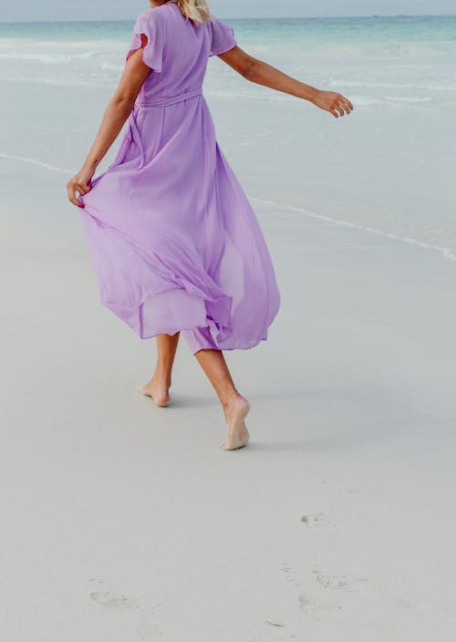 Free Woman in Purple Dress Walking on the Beach Stock Photo