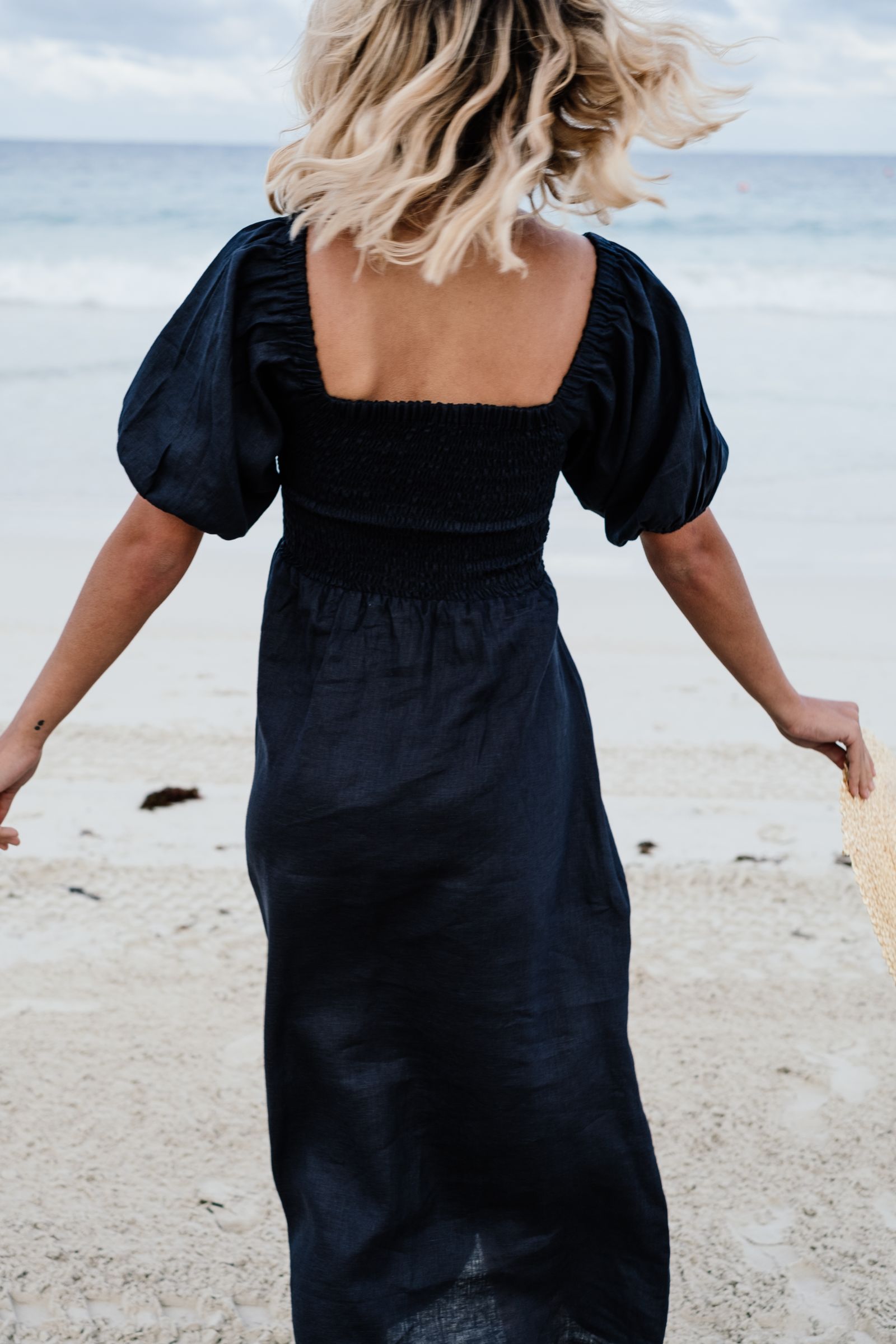 A woman in a black dress at the beach