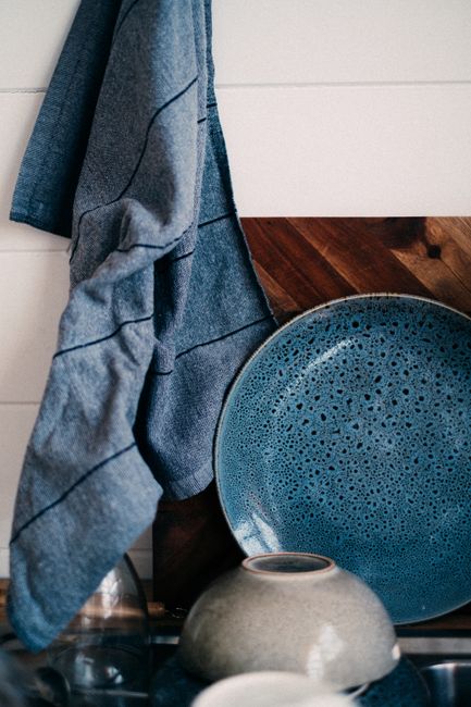 Stylish arrangement of a textured blue plate with a hanging kitchen towel in a modern kitchen.