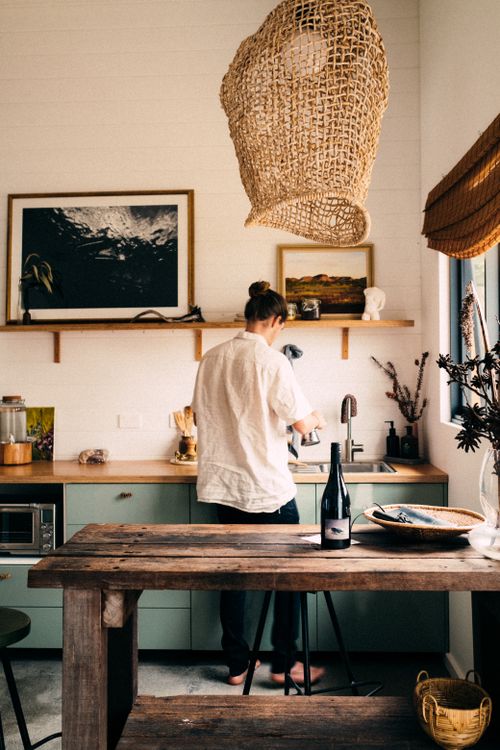Free Man in cozy kitchen preparing food with rustic decor and natural light. Stock Photo