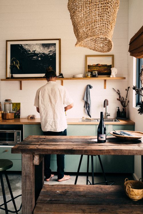 Free A man stands in a rustic kitchen, preparing a meal with wooden accents and warm decor. Stock Photo