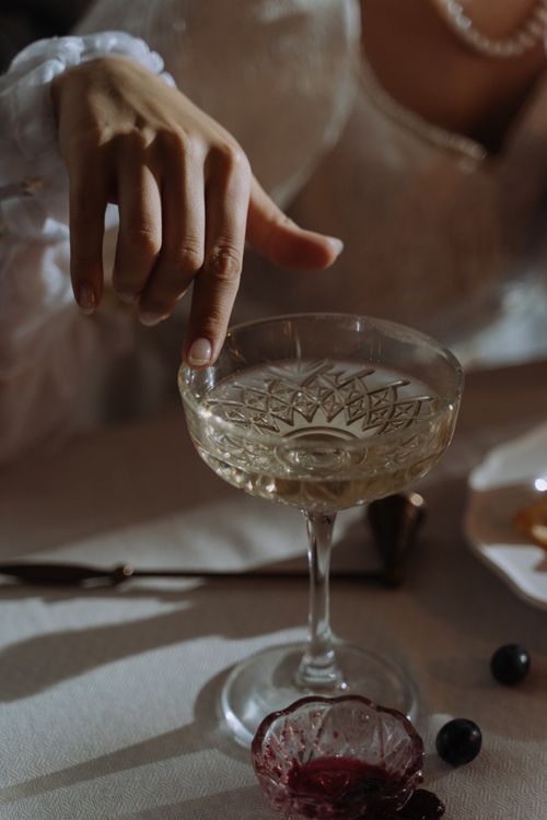 Free A delicate hand reaching for a champagne glass in a serene setting, lit softly for an elegant feel. Stock Photo