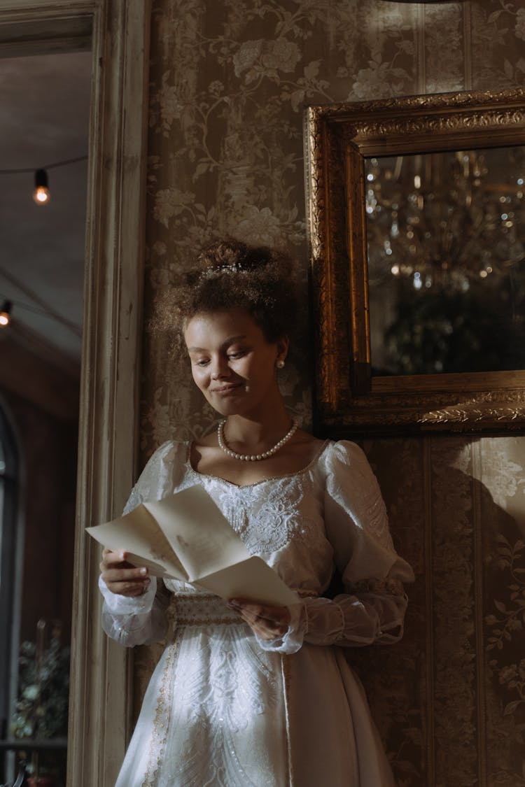 A Woman In A White Dress Reading A Letter 