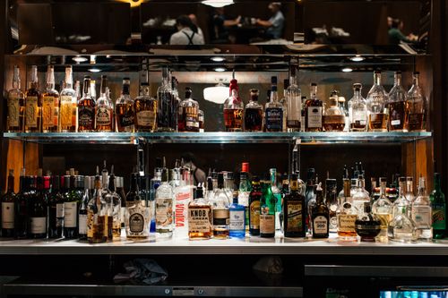 Free A diverse collection of liquor bottles showcased on a well-lit bar shelf. Stock Photo