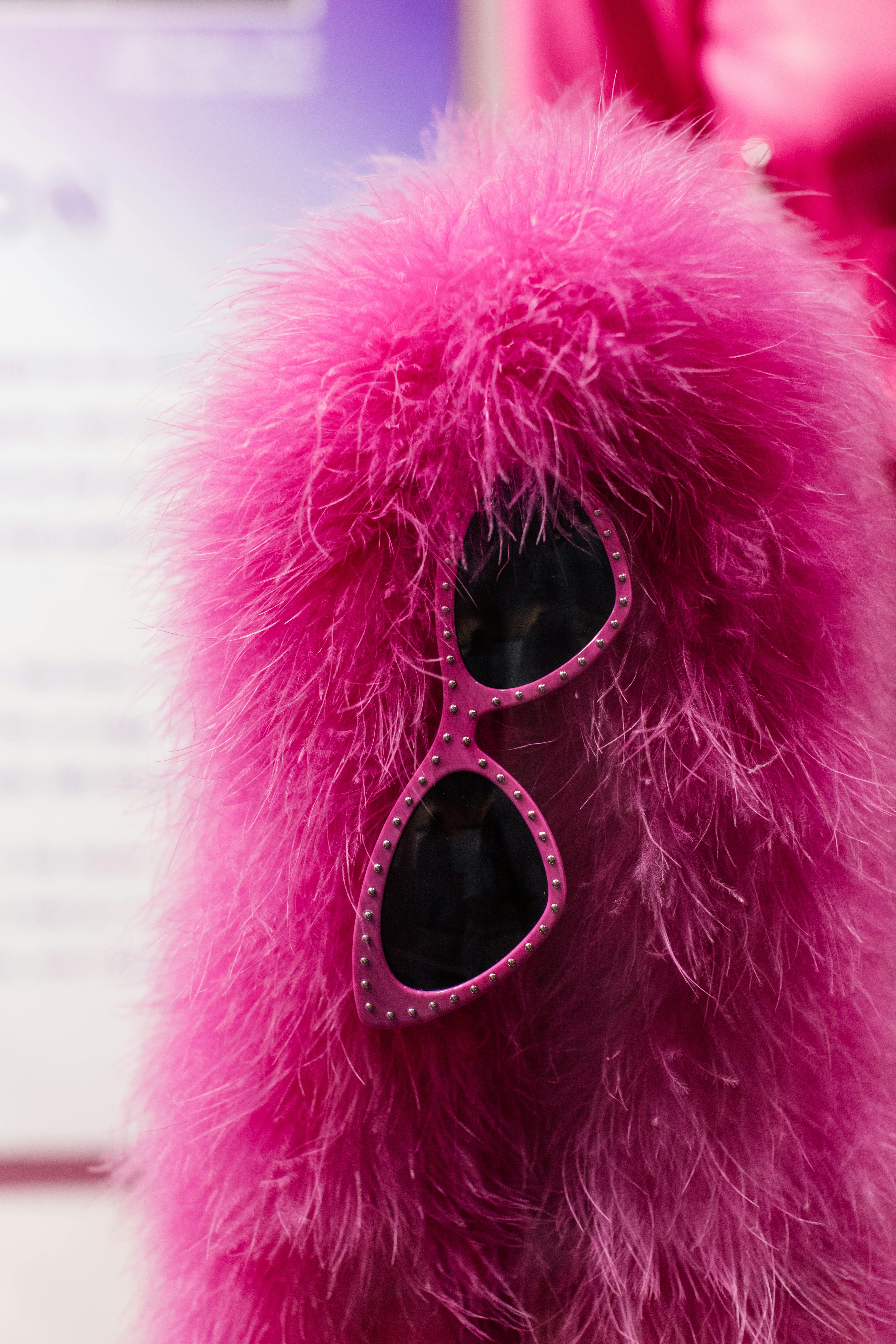 Bright pink faux fur coat with pink sunglasses. Fashion accessory style.