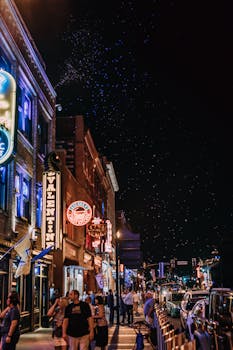 Bustling city street at night with neon lights and people enjoying vibrant nightlife.