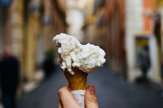 Delicious ice cream cone held up in a blurred urban background, ready to enjoy.