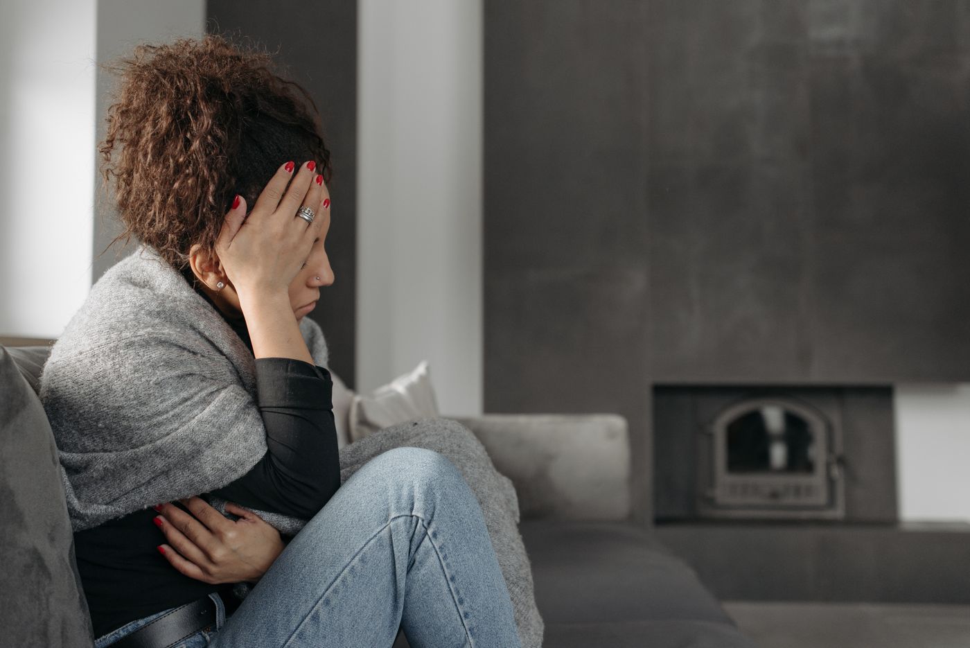 Woman resting on a couch holding her head during a migraine
