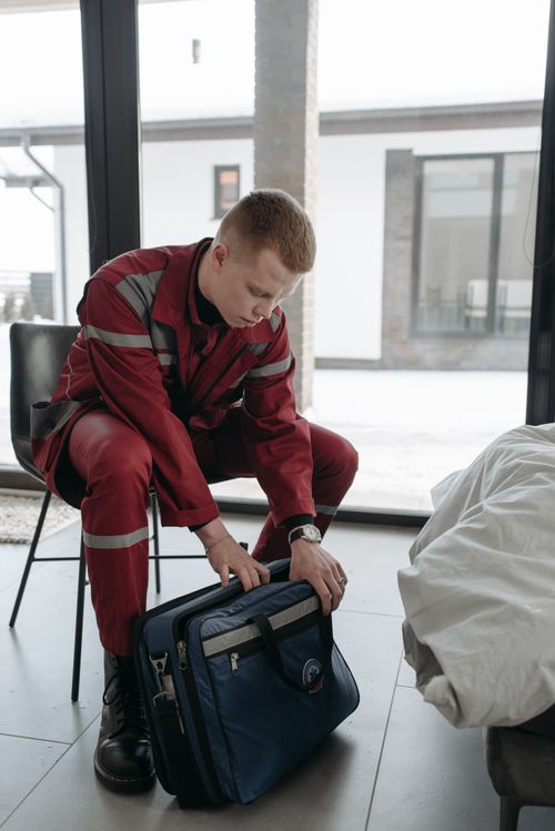 Free A paramedic in red uniform organizes a medical bag inside a building. Stock Photo