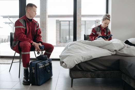 Two paramedics tend to a patient in a modern bedroom, highlighting emergency care services.