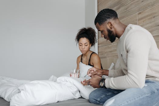 A couple in a bedroom caring for each other during illness. Support and empathy in a home setting.