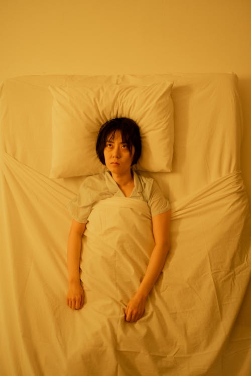 Free A Woman Wide Awake While Lying on the Bed Stock Photo