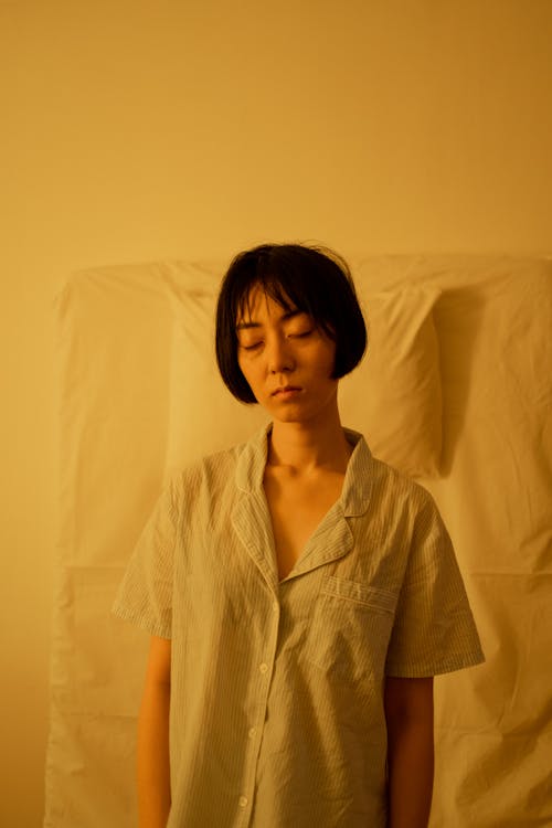 A Woman in Sleepwear Standing while Eyes are Closed