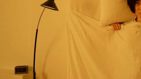 A woman lying awake in bed at 3:33 a.m., showcasing insomnia issues.