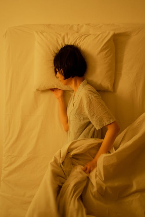 Free A Person in Pajama Lying on the Bed Stock Photo