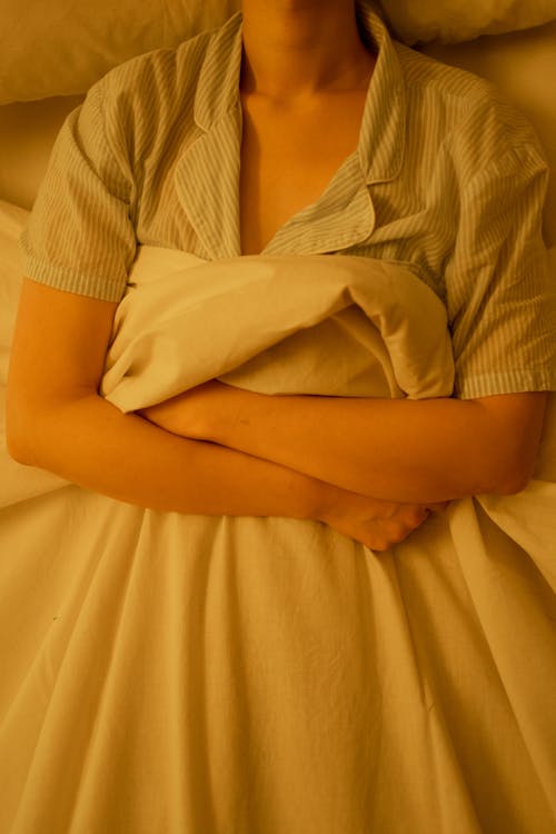 Free A Woman Lying in Bed Grasping a Blanket Stock Photo