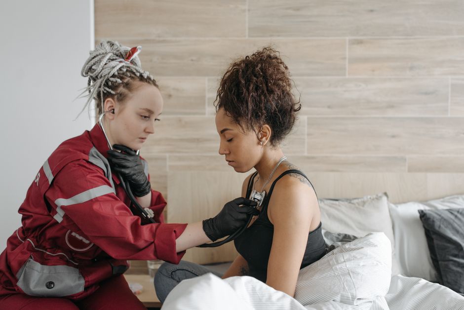 A paramedic checks a patient's vital signs in an indoor home setting, conveying healthcare and care.