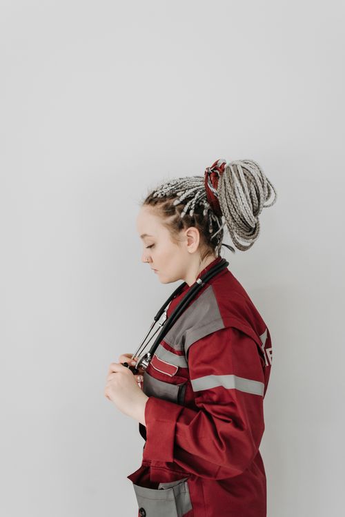 Free Side profile of a female paramedic in uniform adjusting a stethoscope against a white background. Stock Photo