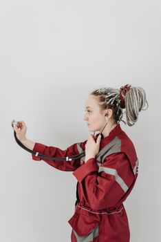 Portrait of a female EMT with braided hair using a stethoscope against a white background.