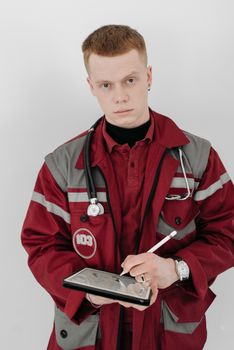 Male paramedic in uniform using a tablet device with a stethoscope around his neck.