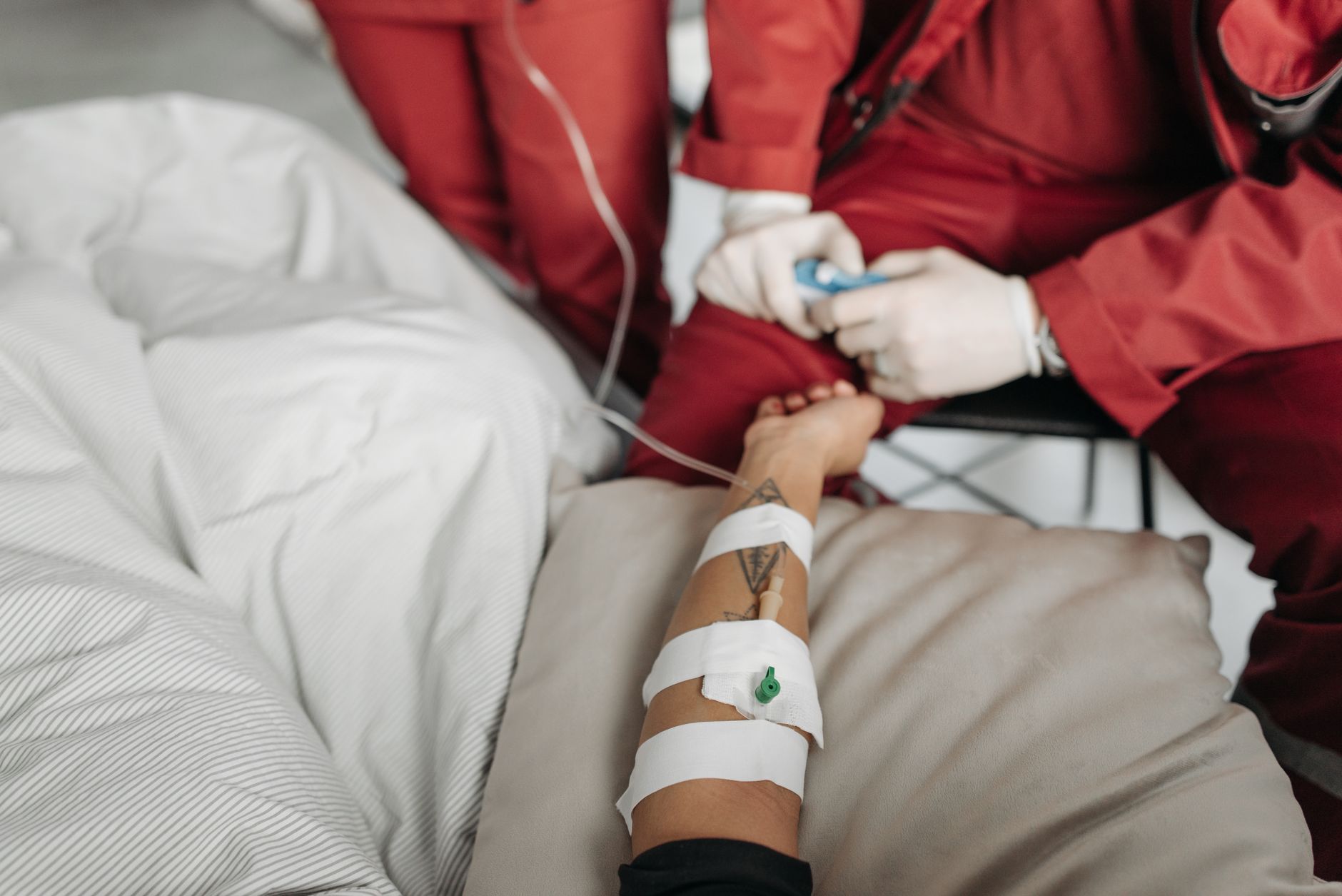 Medical staff attending to a patient with an IV drip in a clinical setting.