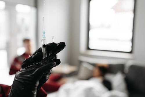 Free Person In Black Gloves Holding A Syringe Stock Photo