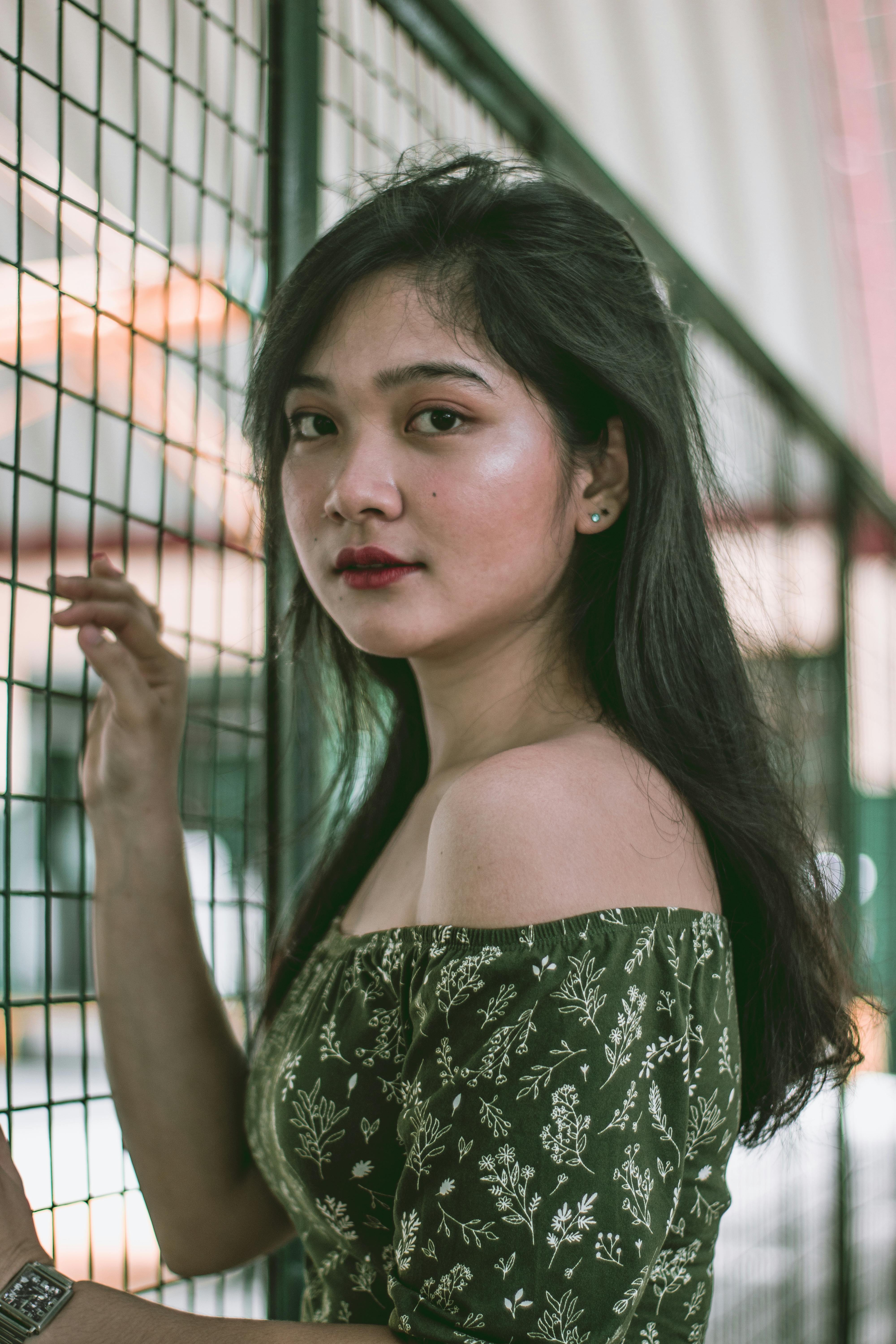 A captivating portrait of an adult woman standing by a metal fence indoors.