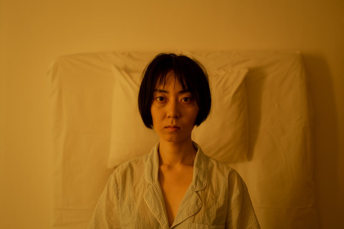An Exhausted Looking Woman in Pajama Lying on Bed