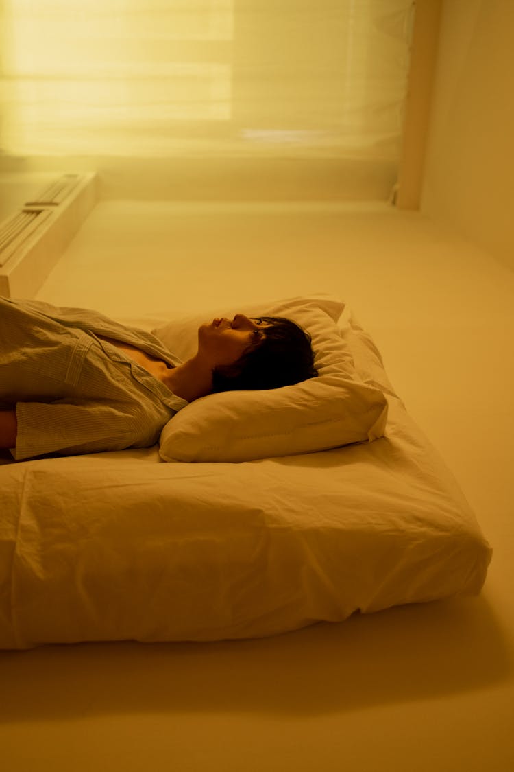 A Woman Lying On Mattress On The Floor