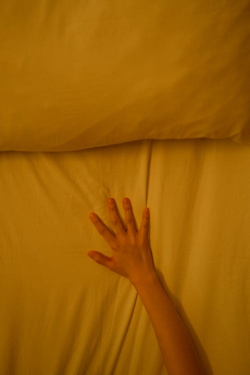 A Person with Hand Touching a Bed