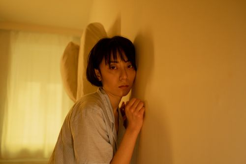 Free A contemplative Asian woman in pajamas leaning against a wall, reflecting emotions. Stock Photo