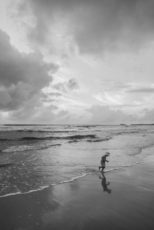 Free Grayscale Photo of a Kid at the Beach Stock Photo
