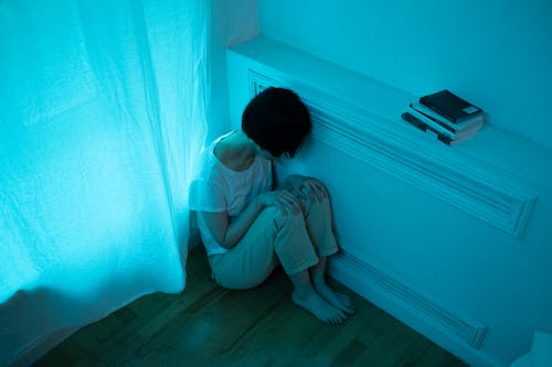 Free A Woman Sitting on the Floor while Leaning on the Wall Stock Photo