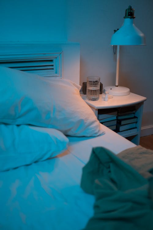 A Lamp and Glass of Water on a Side Table Near the Bed