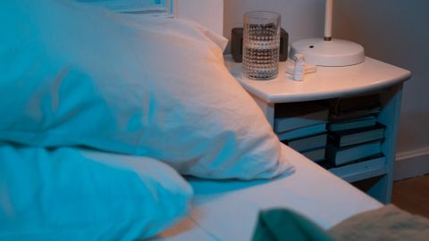 A cozy bedroom scene with a bedside table, lamp, and pillows for a relaxed ambiance.