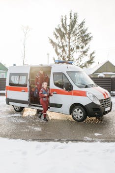 Paramedics stepping out of an ambulance with equipment on a snowy outdoor scene.