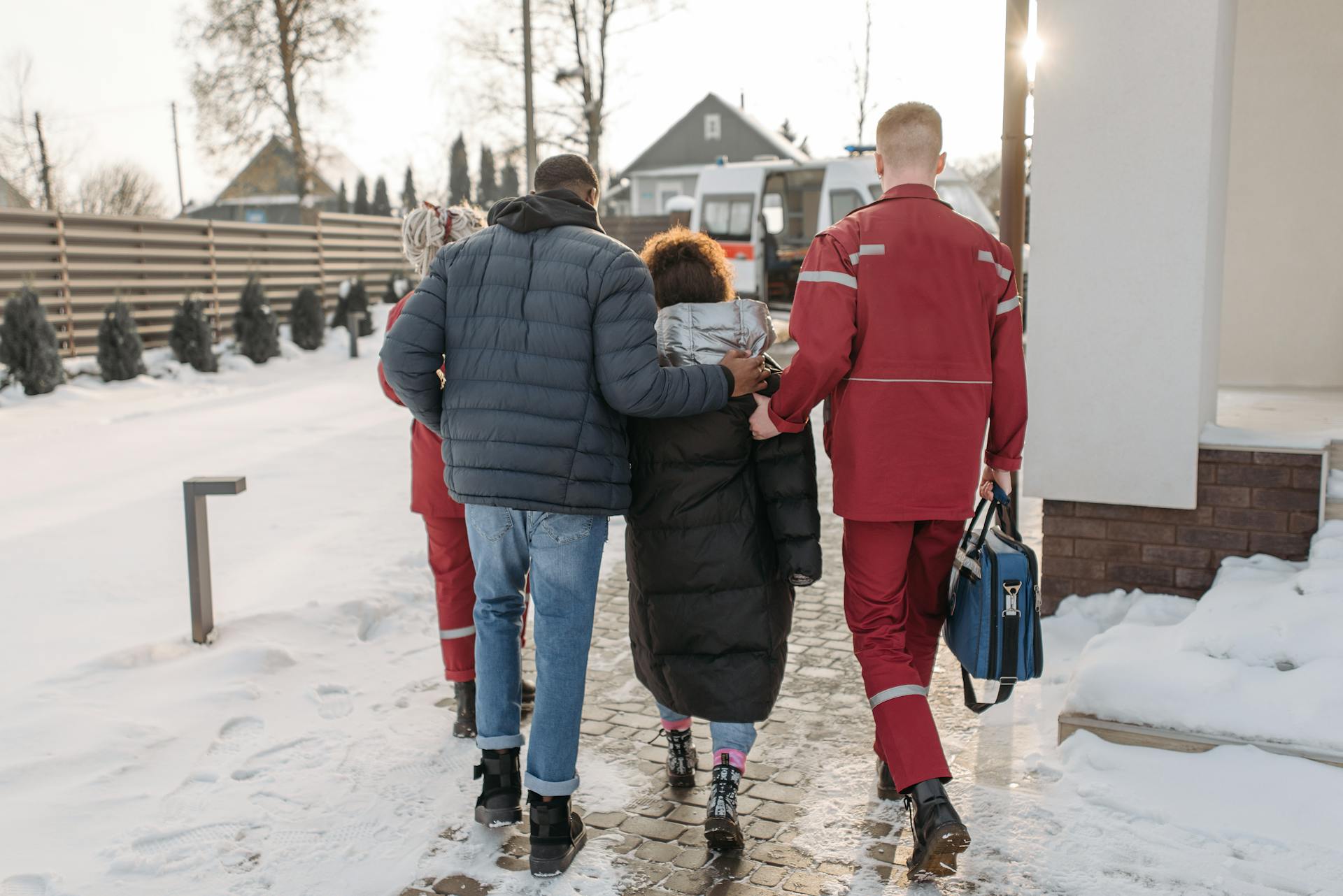 Men Assisting Woman To An Ambulance