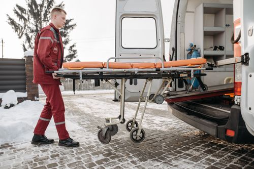 Free A paramedic loads a stretcher into an ambulance on a snowy day, showcasing emergency response readiness. Stock Photo