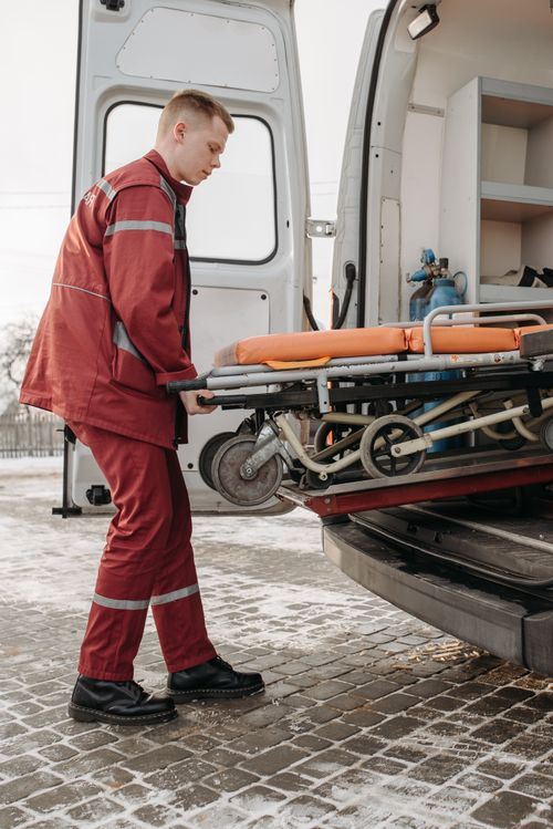 Free A paramedic loads a stretcher into an ambulance outdoors during the day. Stock Photo