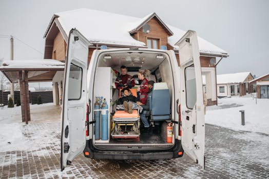 Paramedics assist a patient inside an ambulance during a snowy winter day.