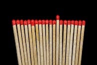 黑色背景前，一排红色尖头木火柴整齐排列