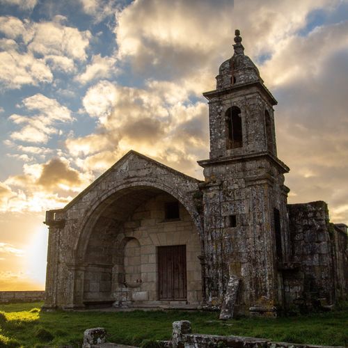 Free Historic stone church against a dramatic sunset sky with clouds. Stock Photo