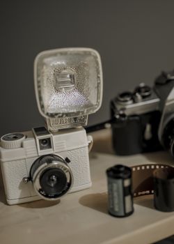 Close-up of vintage cameras, film cartridges, and flash in a studio setting, showcasing classic photography tools.