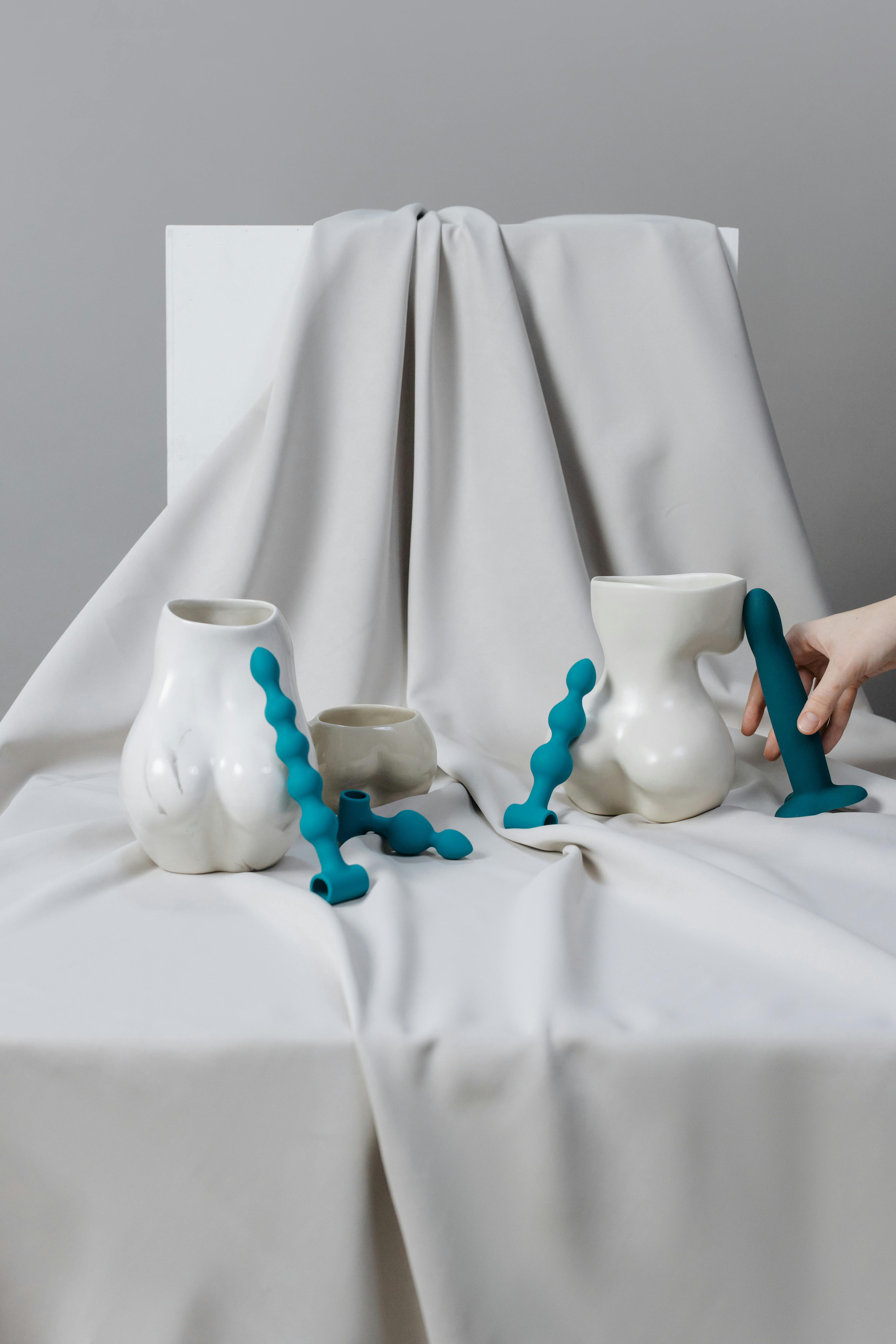 a sex toys on a white surface near the ceramic vases