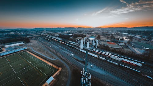 Free Aerial view of industrial district of Chattanooga city with green rugby fields and modern cell tower located near railroad tracks against sunset sky Stock Photo